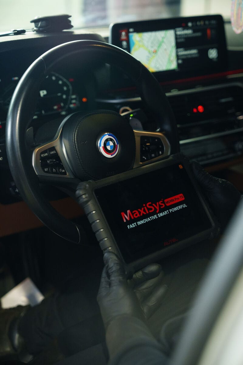Un técnico sostiene una tableta de diagnóstico Autel dentro de un BMW